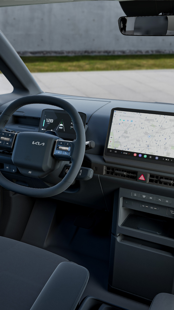 Kia PV5 Passenger cockpit with a digital cluster, heated steering wheel, climate-controlled seats, and navigation display.