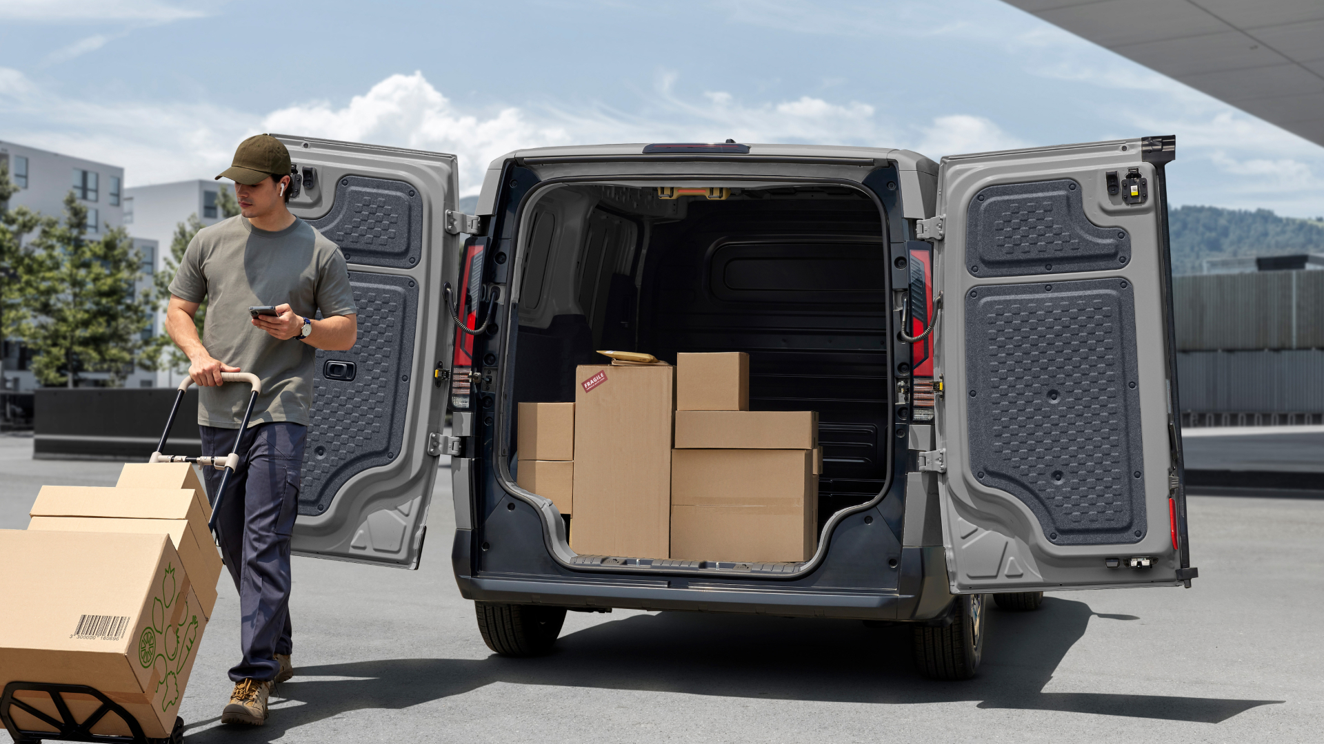 Delivery worker unloading boxes from the Kia PV5 Cargo rear