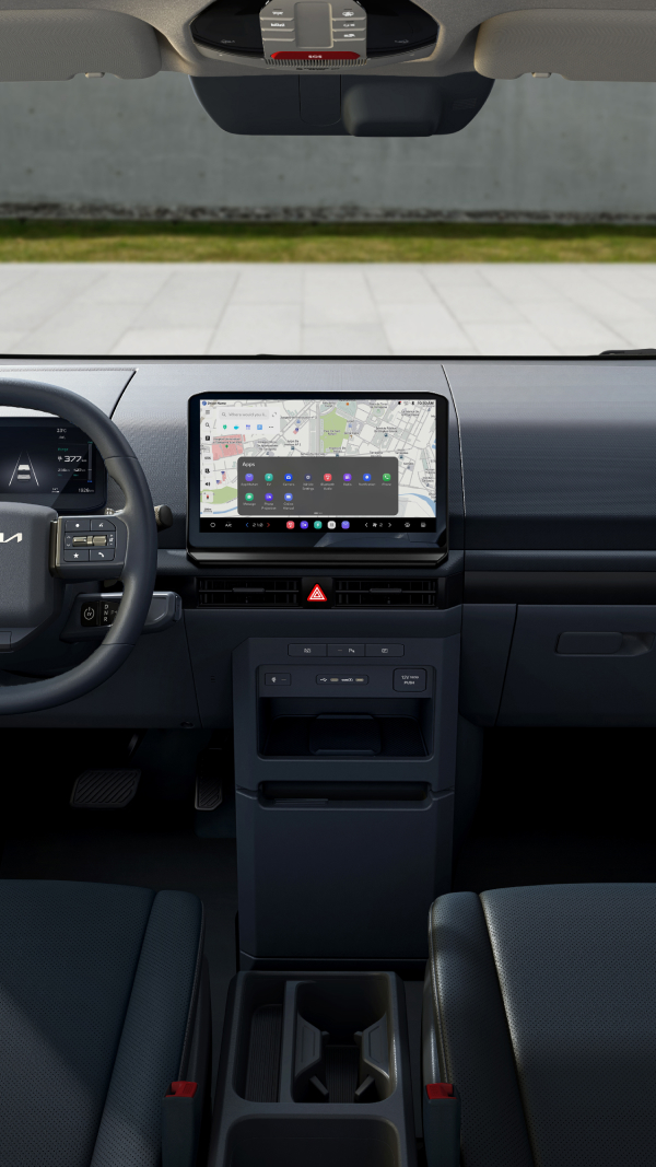 Front driver’s view of Kia PV5 interior showing steering wheel and infotainment display